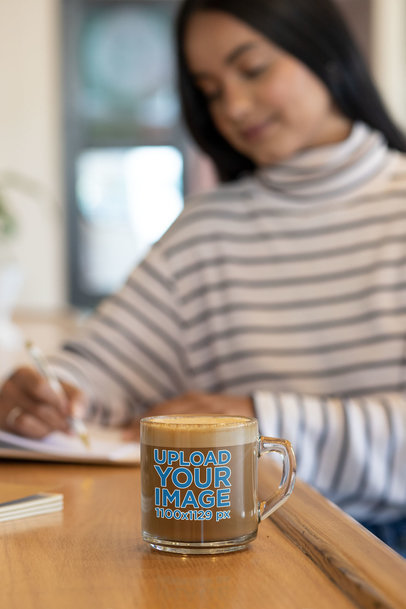 11 oz Clear Mug Mockup Featuring a Woman Writing on a Notebook
