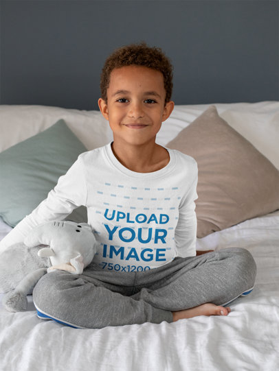 Long Sleeve Tee Mockup Featuring a Kid Sitting on a Bed by a Stuffed Elephant