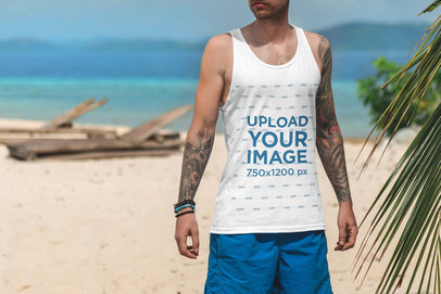 Cropped Face Mockup Featuring a Tattooed Man with a Tank Top at The Beach 