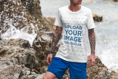 Mockup of a Man Wearing a Customizable T-Shirt Posing by Some Beach Rocks 