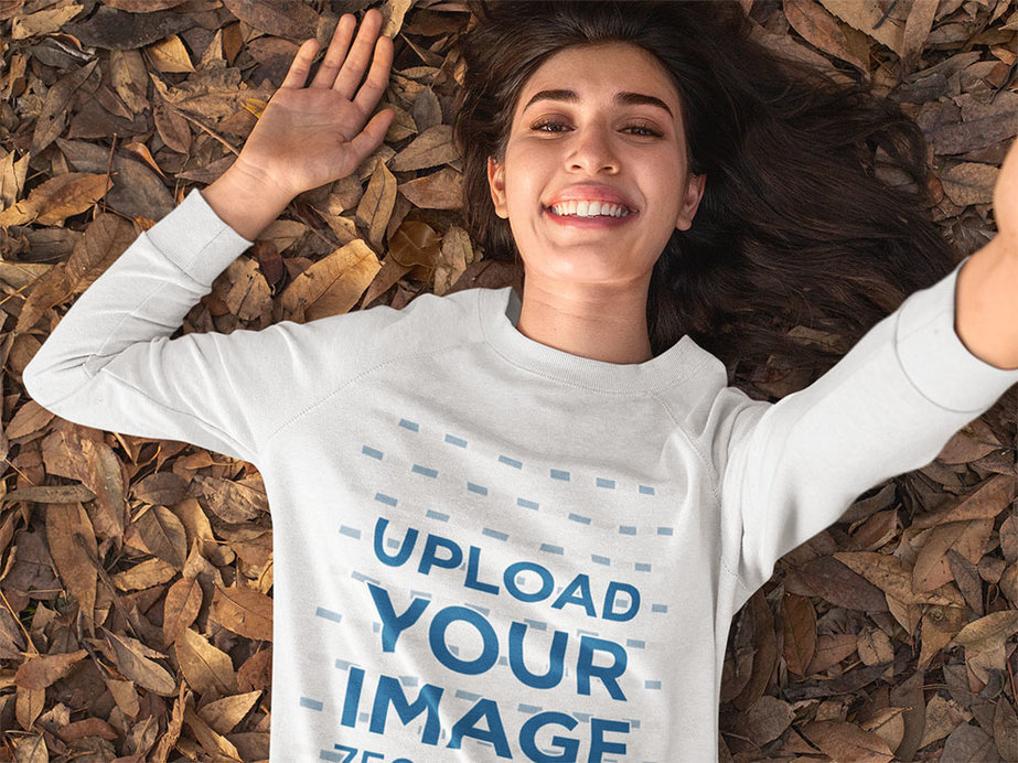 Crewneck Sweatshirt Mockup of a Woman Taking a Selfie While Lying on Some Autumn Leaves