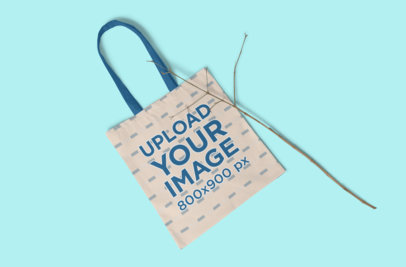 Mockup of a Tote Bag on a Solid Color Surface with a Tree Branch