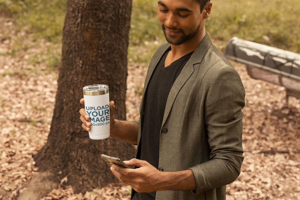 Travel Mug Mockup of a Man Looking at His Phone