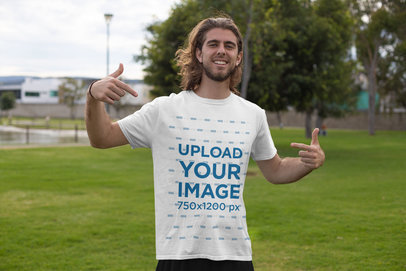 Mockup Featuring a Young Man in the Park Pointing at His Tee 