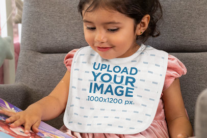 Baby Bib Mockup of a Girl Looking at a Picture Book