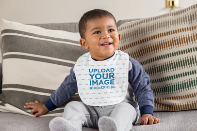 Bib Mockup Featuring a Happy Baby Boy Sitting on a Couch 