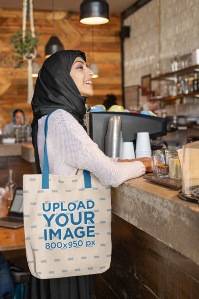 Tote Bag Mockup of a Woman Wearing a Hijab at a Cafe