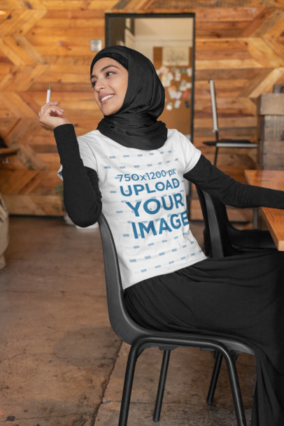 T-Shirt Mockup Featuring a Woman at a Coffee Store Holding a Pen