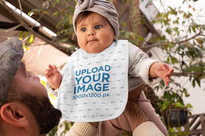 Bib Mockup Featuring a Baby Being Held by Her Dad 