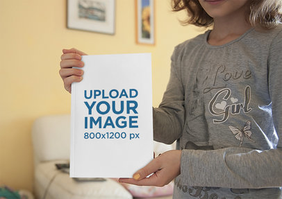 Mockup of a Little Girl Showing the Cover of a Book 3444-el1