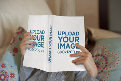 Mockup of a Girl Reading a Paperback Book at Home 