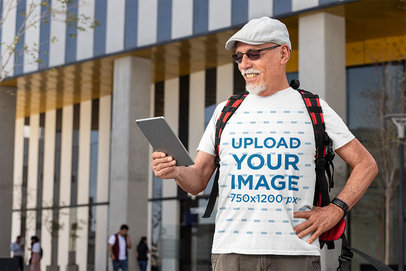 T-Shirt Mockup of a Happy Senior Man Using a Tablet in the Street