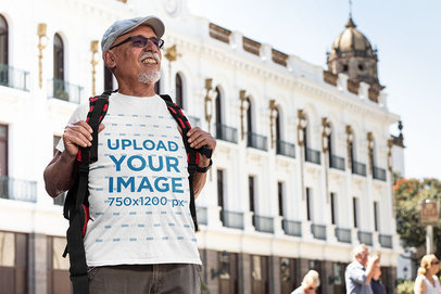 T-Shirt Mockup Featuring a Senior Man Standing in Front of a Classic Building 