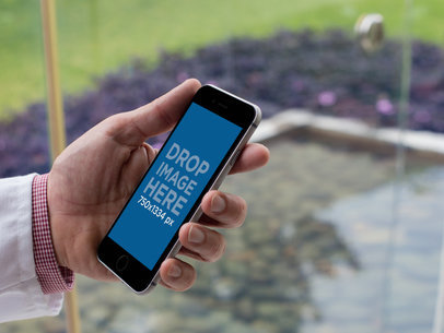 Mockup of a Doctor using an iPhone in Portrait Position with a Background garden