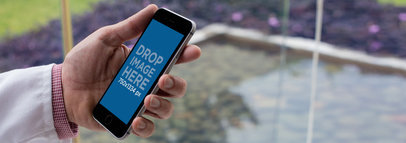 Black iPhone Mockup of a Doctor Holding his iPhone Outside a Hospital