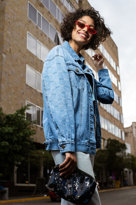 Denim Jacket Mockup Featuring a Woman Posing by a Tall Building