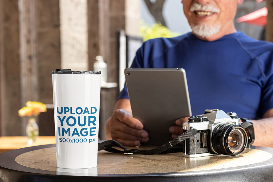 Travel Mug Mockup Featuring a Man Reading at a Coffee Store 