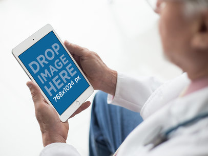 Mockup of a Male Doctor Looking at an iPad in Portrait Position