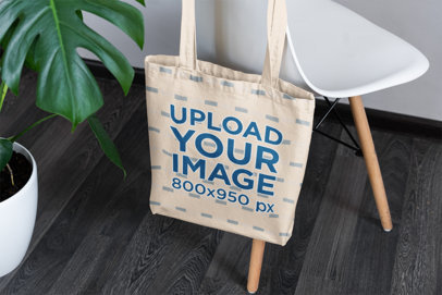 Sublimated Tote Bag Mockup Featuring a Modern Chair and a Plant 