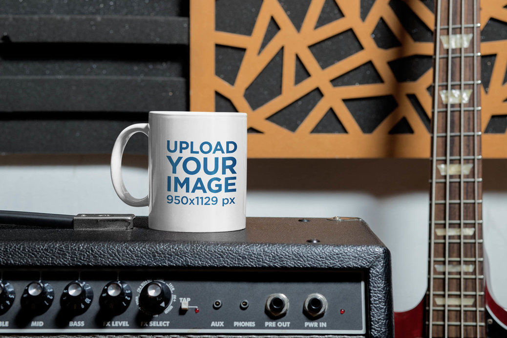 Mockup of an 11 oz Coffee Mug Placed Next to a Bass Guitar 