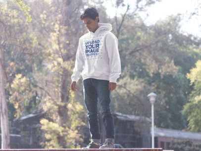 Pullover Hoodie Mockup of a Guy Standing in a Park and Looking Down