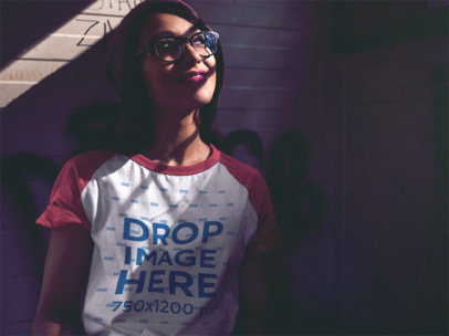 Mockup of a Trendy Woman with Glasses Wearing a Raglan Tee in the Shadows
