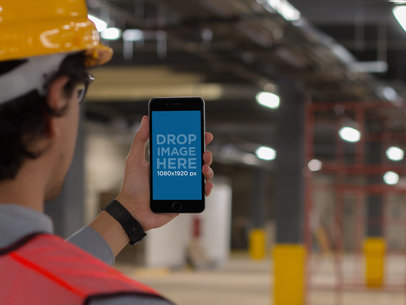 Mockup Featuring a Male Worker Staring at an iPhone Inside a Factory