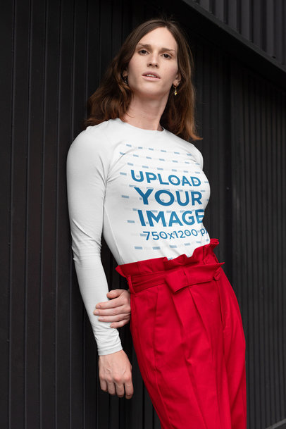 Mockup of a Woman Wearing a Customizable Long Sleeve Tee and Leaning Against a Dark Wall