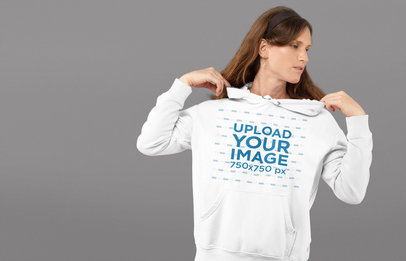 Mockup of a Woman Fixing Her Hoodie in a Studio