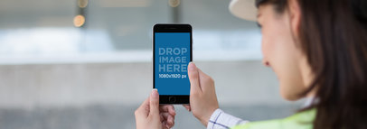 Mockup of an iPhone 6 Plus Held by a Female Architect at a Construction Site