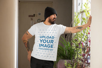 Mockup of a Man Wearing a Customizable T-Shirt and Looking Through a Window