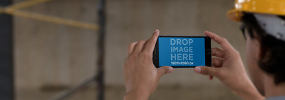 Mockup of a Construction Worker Holding an iPhone in Landscape Position 