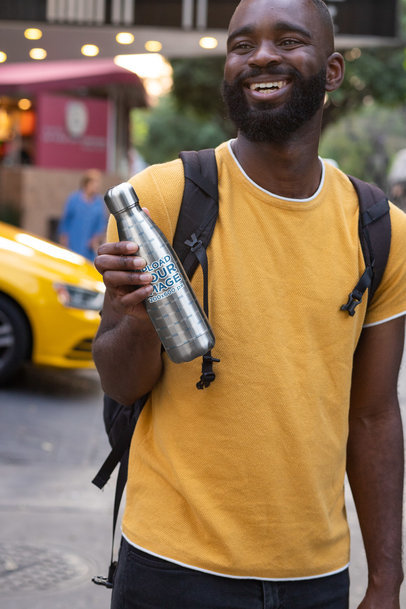 Mockup Featuring a Happy Man Holding a Sublimated Aluminum Bottle Outside