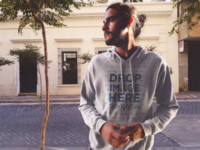 Guy with Long Hair in a Man Bun Wearing a Pullover Heather Hoodie Mockup in the Street