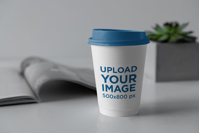 Mockup of a Coffee Cup With a Colored Lid Placed on a Clear Surface 