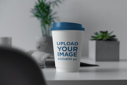 Mockup of a Coffee Cup with Customizable Lid Placed on a Desk 