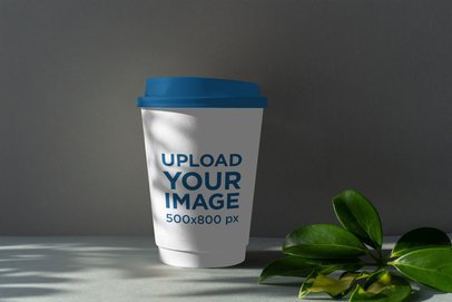 Mockup Featuring a Coffee Cup With a Colored Lid Placed by Some Leaves 