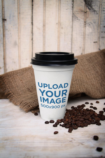 Mockup of a Customizable Paper Cup Placed by Some Coffee Beans