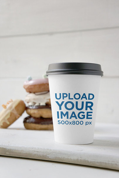 Coffee Cup Mockup Featuring a Pile of Decorated Donuts 
