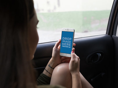 Mockup of a Woman Holding an iPhone in Portrait Position in a Car