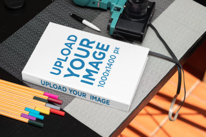 Mockup of a Hardcover Book Placed by Some Markers and a Vintage Camera 33903