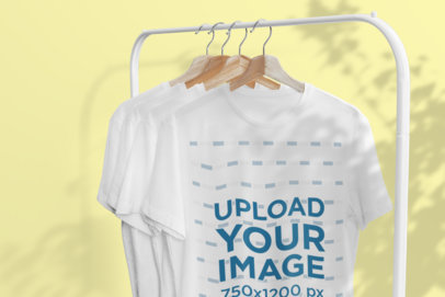 Mockup of a T-Shirt Hanging From a Rack With Plant Shadows in the Background 