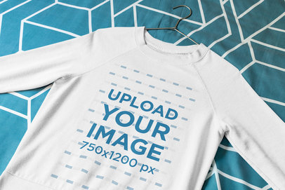 Mockup of a Sweatshirt with a Hanger Laid Flat on a Bed