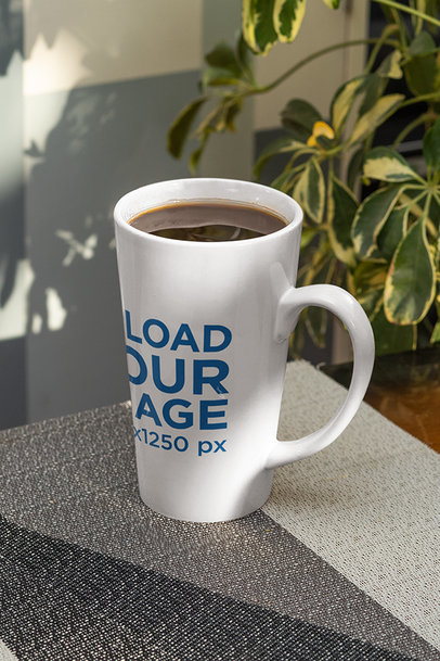 Mockup of a 15 oz Conical Mug Placed by an Indoor Plant