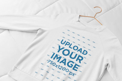 Mockup of a Women's Sweatshirt with a Hanger Laid Flat on a Bed