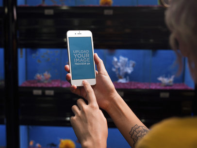 Mockup of a Woman Looking at an iPhone in Portrait Position