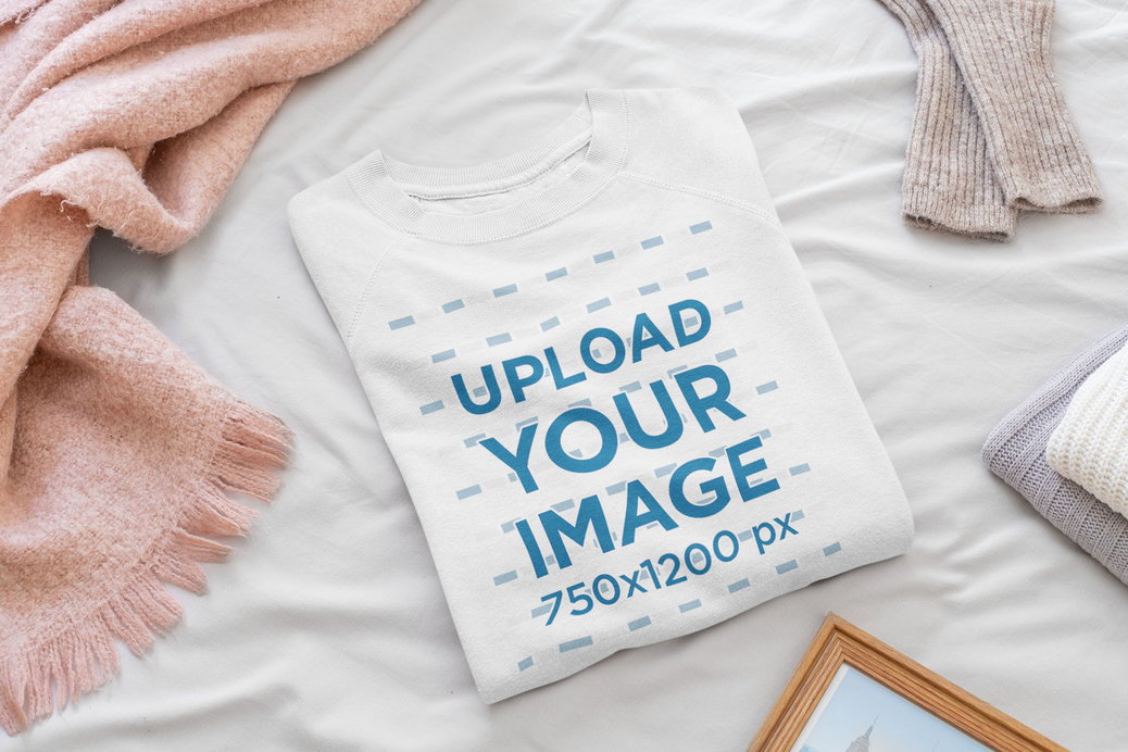 Mockup Featuring a Folded Women's Crewneck Sweatshirt Placed on a Bed 