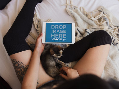 White iPad Mini Mockup of a Woman Sitting in Bed with her Kitten a12812