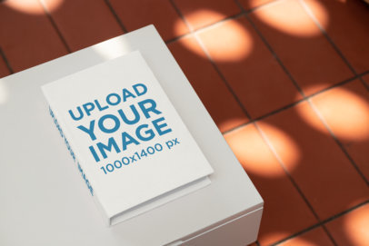 Mockup of a Hardcover Book With a Customizable Spine Placed on a Small Table 33912