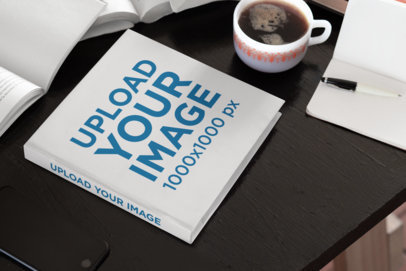 Mockup of a Hardcover Square Book Placed on a Work Desk 